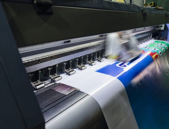 Large format inkjet printer machine working on vinyl paper in workplace