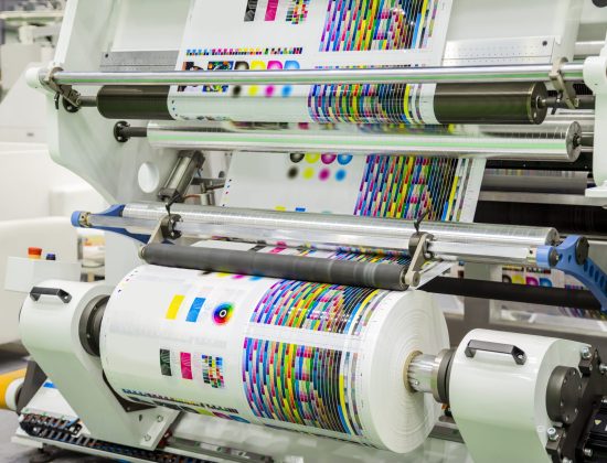 Large offset printing press or magazine running a long roll off paper in production line of industrial printer machine.